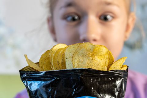Mädchen schaut auf eine Chipstüte
