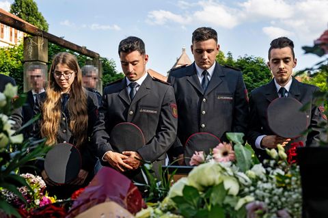 Mannheim: Drei Männer und eine Frau stehen vor Blumen und halten den Kopf zum Gedenken gesenkt.