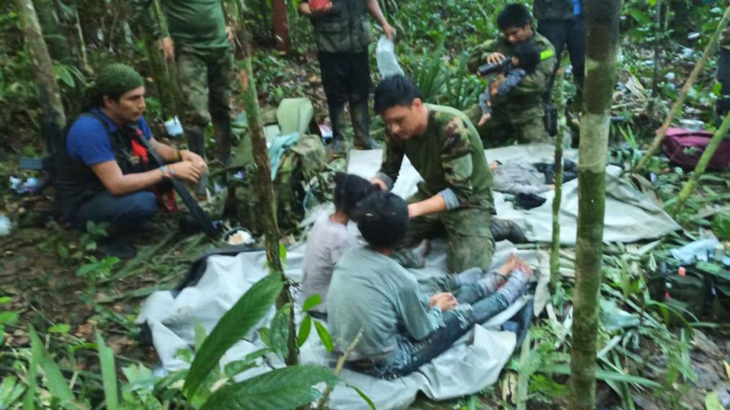 Soldaten und indigene Männer kümmern sich im Dschungel von Kolumbien um die vier Geschwister