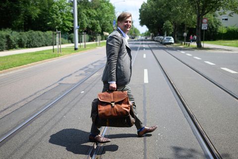 Maximilian Krah läuft mit einer dicken Aktentasche über eine Straße