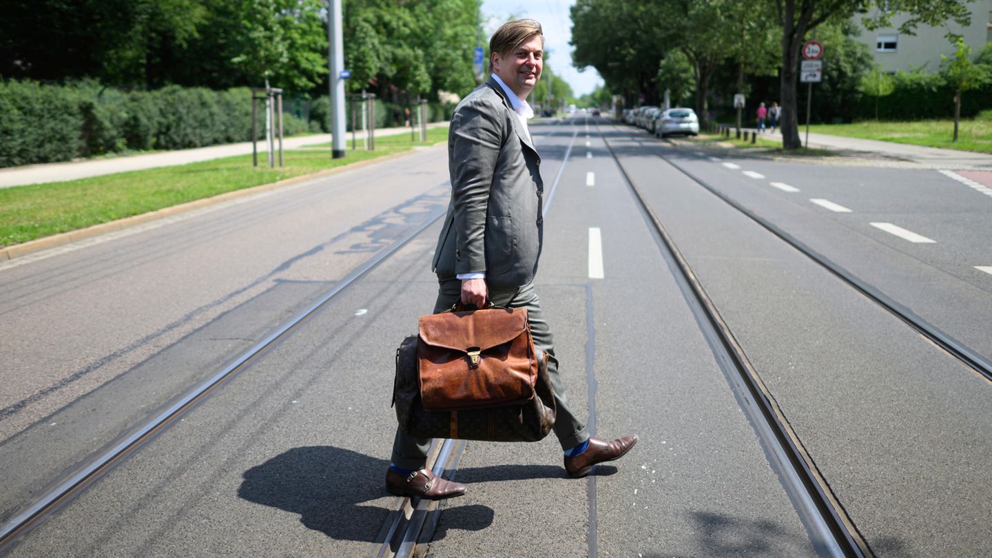 Maximilian Krah läuft mit einer dicken Aktentasche über eine Straße