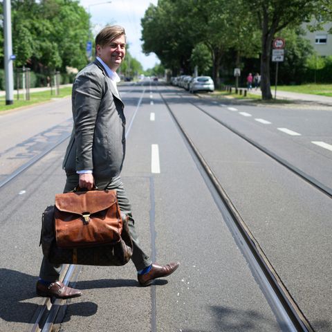 Maximilian Krah läuft mit einer dicken Aktentasche über eine Straße