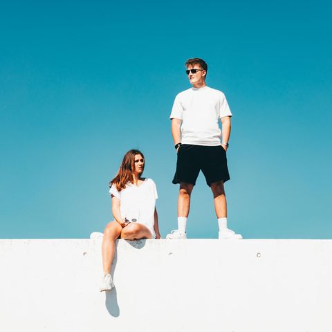 Jugendliche chillen auf einer Mauer vor blauem Himmel