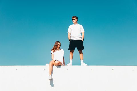 Jugendliche chillen auf einer Mauer vor blauem Himmel