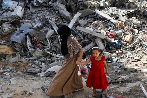 Eine Frau und ein Kind laufen durch die Trümmer eine Flüchtlingscamps im Gazastreifen