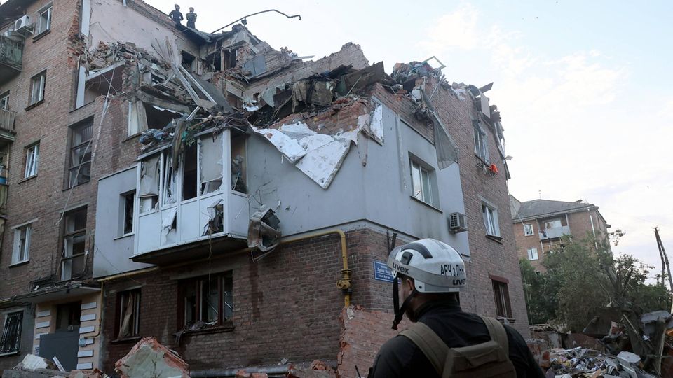 Helfer vor einem zerstörten Haus in Charkiw, Ukraine