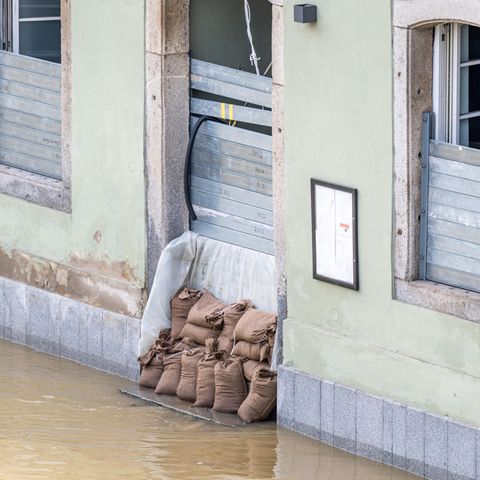 Pflichtversicherung ja oder nein? Ein Haus im Hochwasser, das mit Sandsäcken geschützt ist
