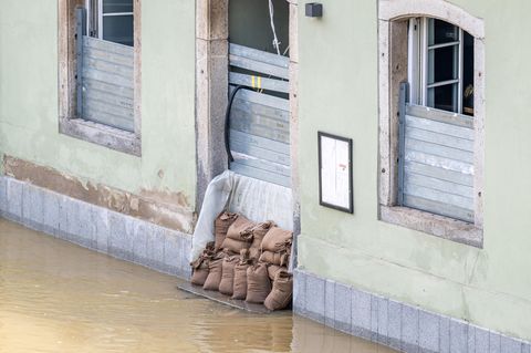 Pflichtversicherung ja oder nein? Ein Haus im Hochwasser, das mit Sandsäcken geschützt ist