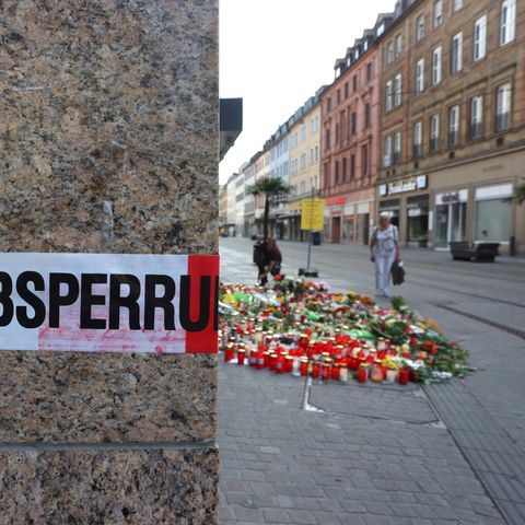 Blumen und Kerzen vor einem abgesperrten Kaufhaus in Würzburg, in dem ein Mann 2021 Menschen mit einem Messer attackiert hatte