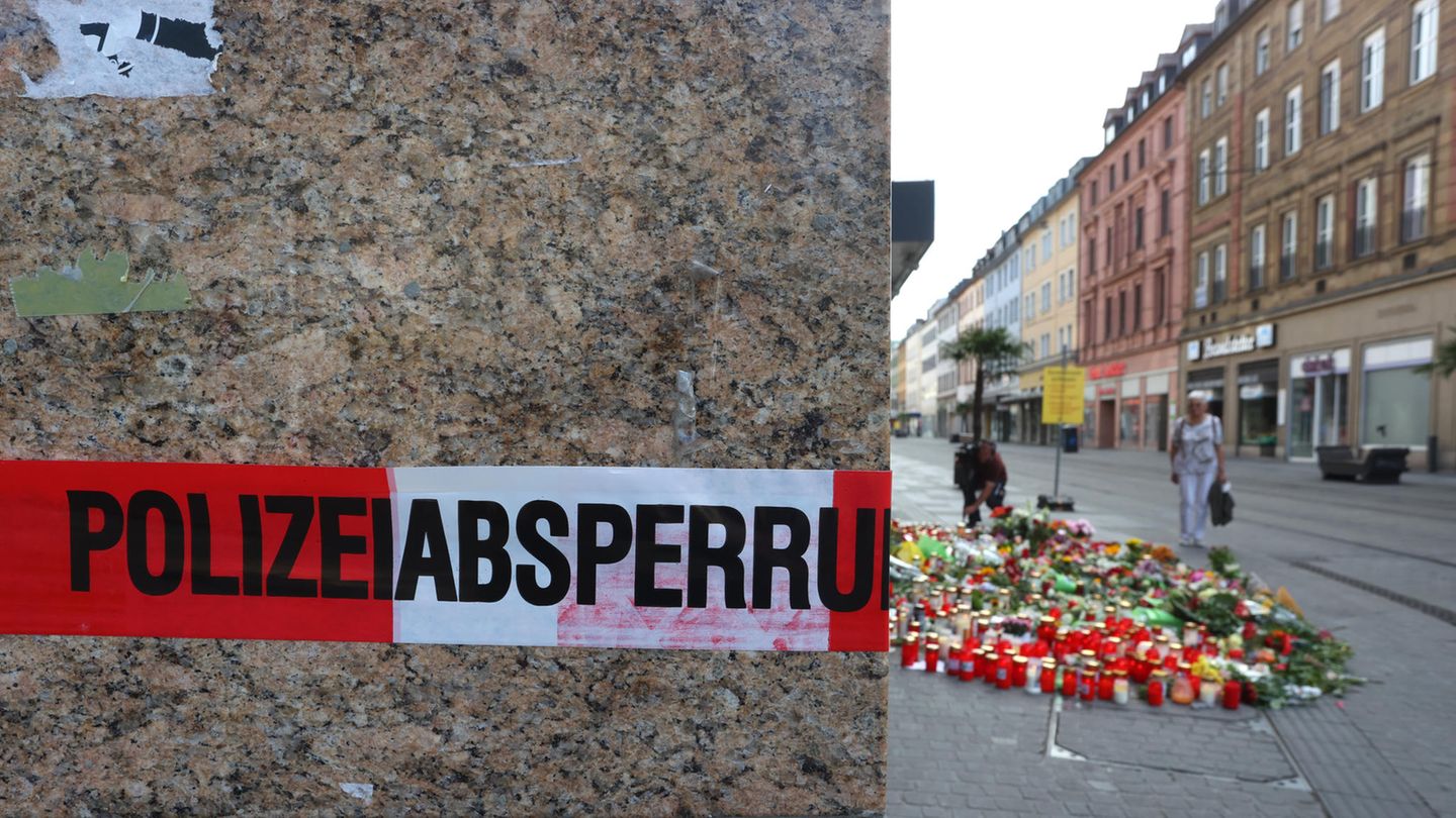 Blumen und Kerzen vor einem abgesperrten Kaufhaus in Würzburg, in dem ein Mann 2021 Menschen mit einem Messer attackiert hatte