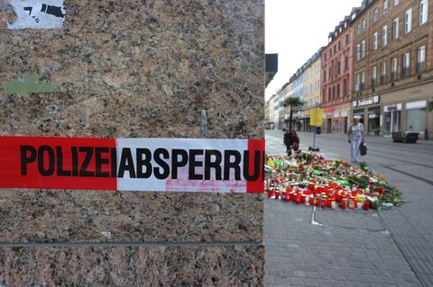 Blumen und Kerzen vor einem abgesperrten Kaufhaus in Würzburg, in dem ein Mann 2021 Menschen mit einem Messer attackiert hatte