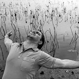 Mahdi steht mit ausgebreiteten Armen an einem See