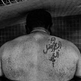 Shahram in einem Bad, fotografiert von hinten, man sieht eine Tätowierung auf der rechten Schulter