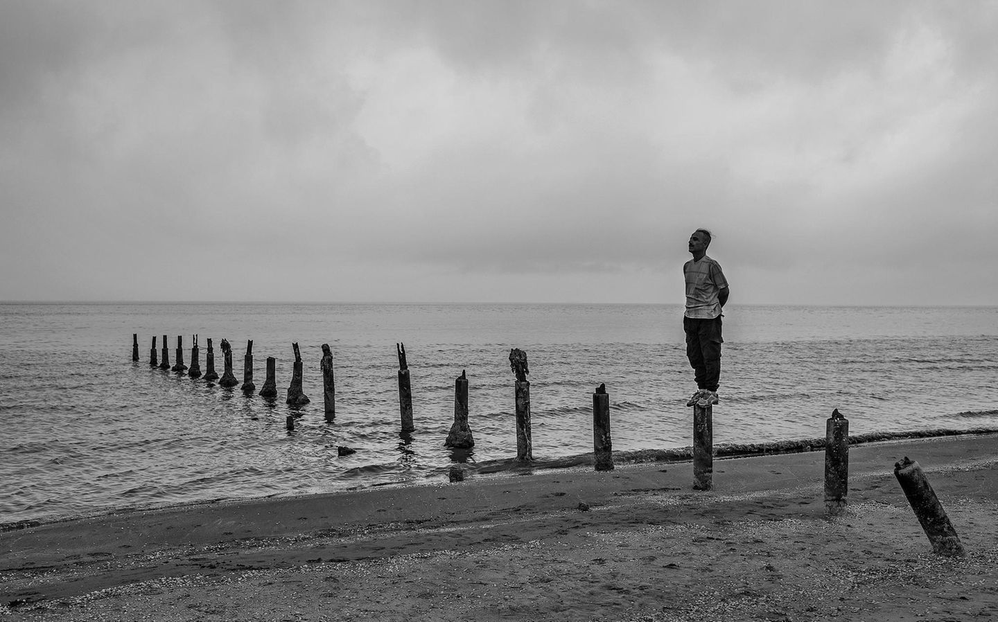Rostam Rostam steht auf einem Pfahl eines verrotteten Stegs am Strand