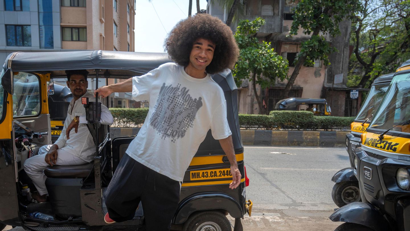 Influencer und Tiktok-Star Noel Robinson steigt aus einer Rikscha auf die Straße, er hat eine Afro und trägt ein weißes Shirt