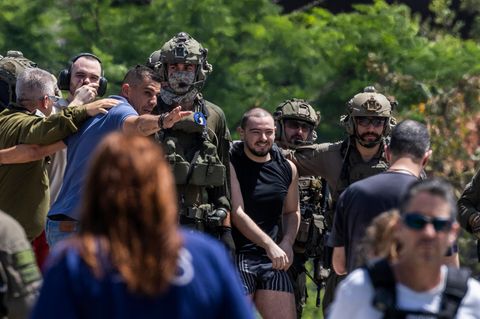 Almog Meir (C), 21, kommt von Soldaten begleitet in Israel an. Er lächelt.
