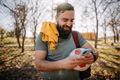 Mann mit Fußball und Handy freut sich über Klarmobil-Deal zur EM.
