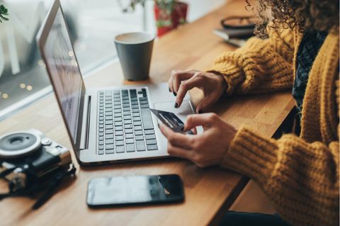 Kreditkarte überziehen: Frau mit Kreditkarte am Computer.