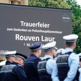 Kollegen des getöteten Polizisten haben sich in Mannheim vor einer Leinwand versammelt