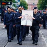 Beim Trauermarsch der Beamten tragen Polizisten das Bild ihres getöteten Kollegen ganz vorne