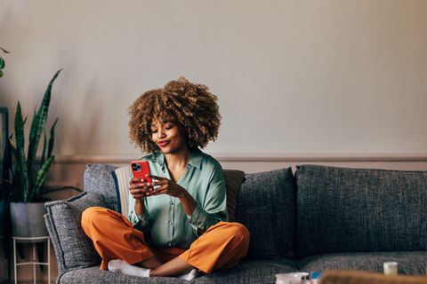 Frau mit iPhone 15 auf Sofa.