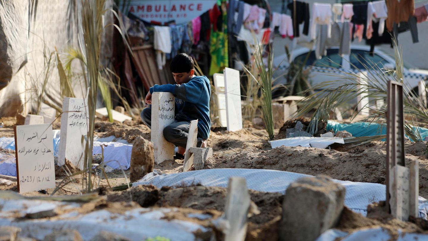 Ein Junge kniet am Grab eines Opfers des Krieges im Gazastreifen