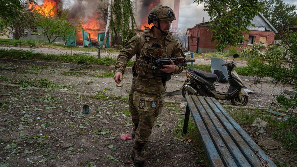 Ukraine, Wowtschansk: Ein Polizist läuft vor einem brennenden Haus, das durch einen russischen Luftangriff zerstört wurde