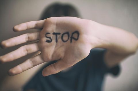 Eine Frau hält ihre Hand vors Gesicht, auf der Innenfläche steht "Stop"