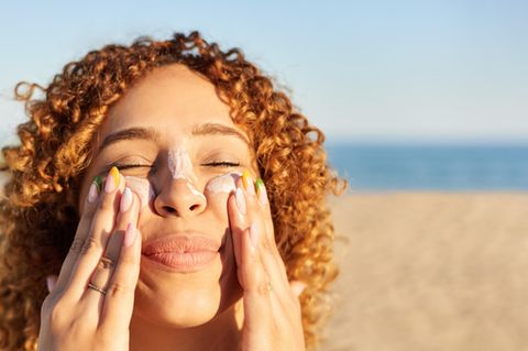 Frau trägt sich Sonnencreme im Gesicht auf – Stiftung Warentest hat Sonnenschutzmittel getestet