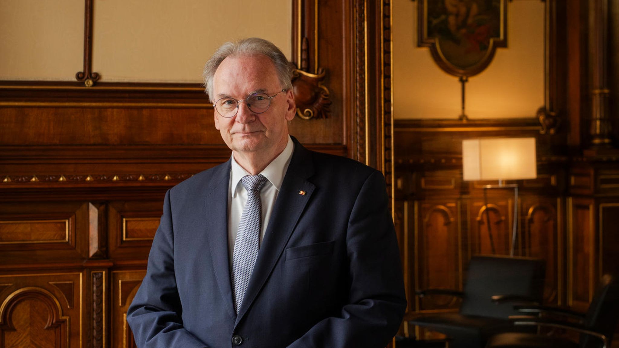 Deutschlands dienstältester Ministerpräsident: Reiner Haseloff steht im Anzug vor einer Holz vertäfelten Wand