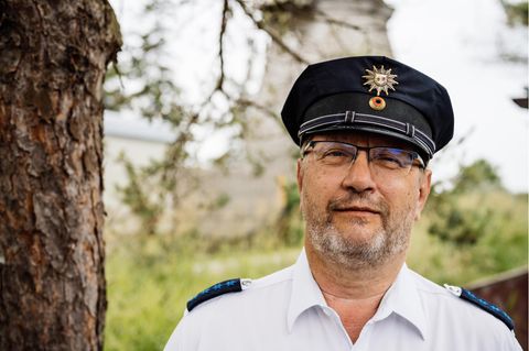 Polizist Thomas Moritz in Uniform. Er steht vor einem Baum und schaut in die Kamera