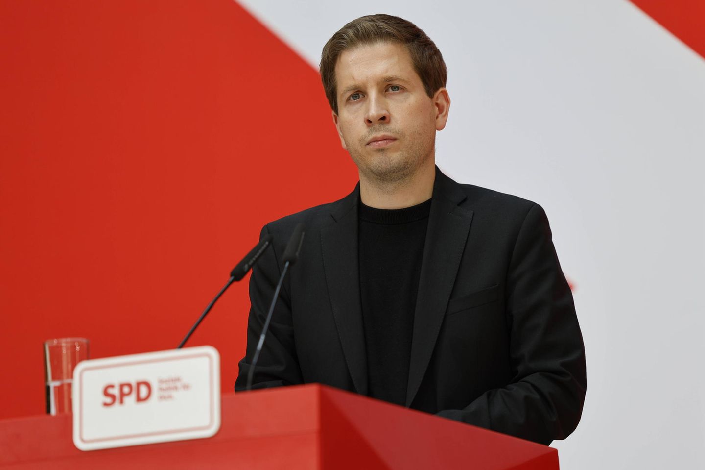 Kevin Kühnert steht bei einer Pressekonferenz am Rednerpult. Sein Gesichtsausdruck ist ernst.
