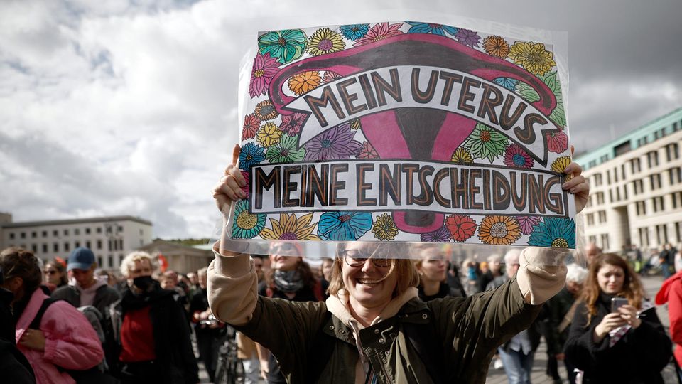 Eine Frau hält auf einer Demo ein Plakat in die Kamera auf dem steht "Mein Uterus, meine Entscheidung"