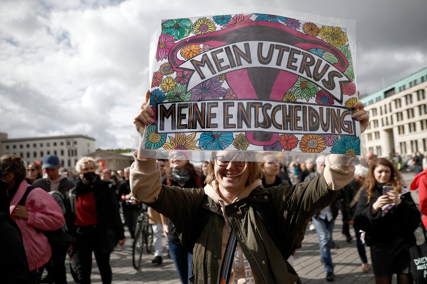 Eine Frau hält auf einer Demo ein Plakat in die Kamera auf dem steht "Mein Uterus, meine Entscheidung"