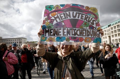 Eine Frau hält auf einer Demo ein Plakat in die Kamera auf dem steht "Mein Uterus, meine Entscheidung"