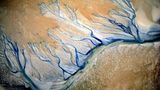 Wie adern zieht sich ein blauer Fluss durch den Sand