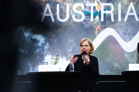 Umweltministerin Leonore Gewessler (Grüne) hält eine Rede im Hintergrund das Wort Austria (Österreich)