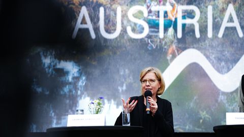 Umweltministerin Leonore Gewessler (Grüne) hält eine Rede im Hintergrund das Wort Austria (Österreich)
