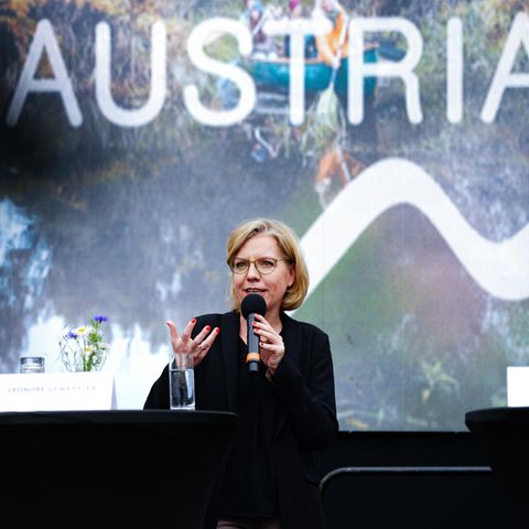 Umweltministerin Leonore Gewessler (Grüne) hält eine Rede im Hintergrund das Wort Austria (Österreich)