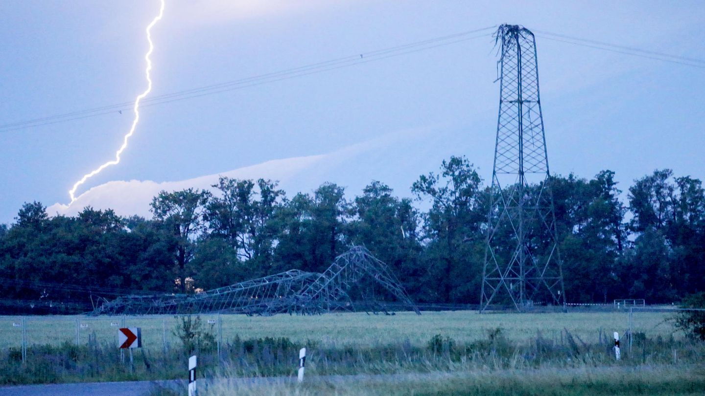 Ein Blitz schlägt neben einem umgeknickten Strommast ein