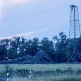 Ein Blitz schlägt neben einem umgeknickten Strommast ein