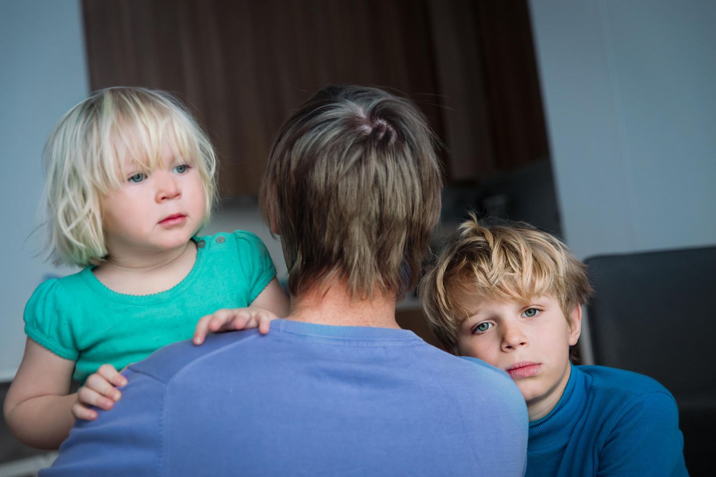 zwei Kinder schauen ber den Rücken eines Elternteiles.
