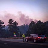 Der Rauch des South Fork Fire spiegelt bei Sonnenaufgang einen rosafarbenen Farbton wider, als Polizisten Autofahrer auf der State Road 48 an der State 220 wegen der Waldbrände in der Nähe von Ruidoso, New Mexico, anhalten