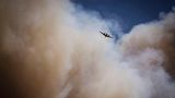 Fast schon winzig erscheint das Löschflugzeug vor den Rauchwolken über dem Waldbrand bei Ruidoso
