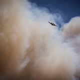 Fast schon winzig erscheint das Löschflugzeug vor den Rauchwolken über dem Waldbrand bei Ruidoso