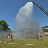 Kinder erfrischen sich unter dem Wasserstrahl, der von einem Leiterwagen auf einen Park in Benton Benton Harbor, Michigan, niedergeht