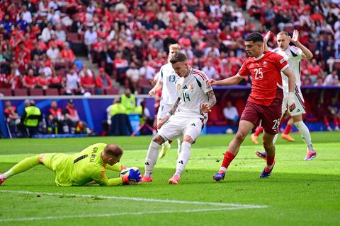 Torwart hält liegend ausgestreckt den Ball fest, während zwei Spieler vor ihm stoppen