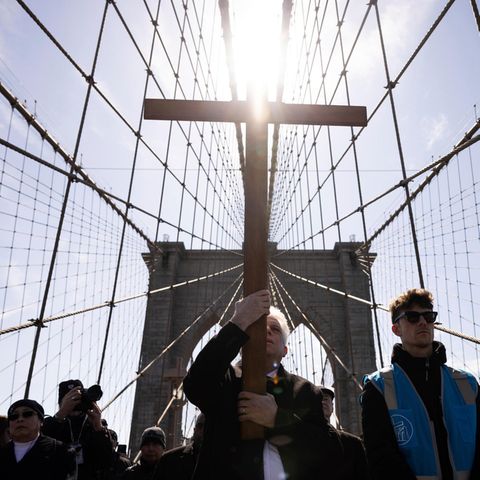 Menschen tragen ein Kreuz bei einer religiösen Prozession über die Brooklyn Bridge in den USA