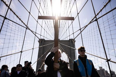 Menschen tragen ein Kreuz bei einer religiösen Prozession über die Brooklyn Bridge in den USA