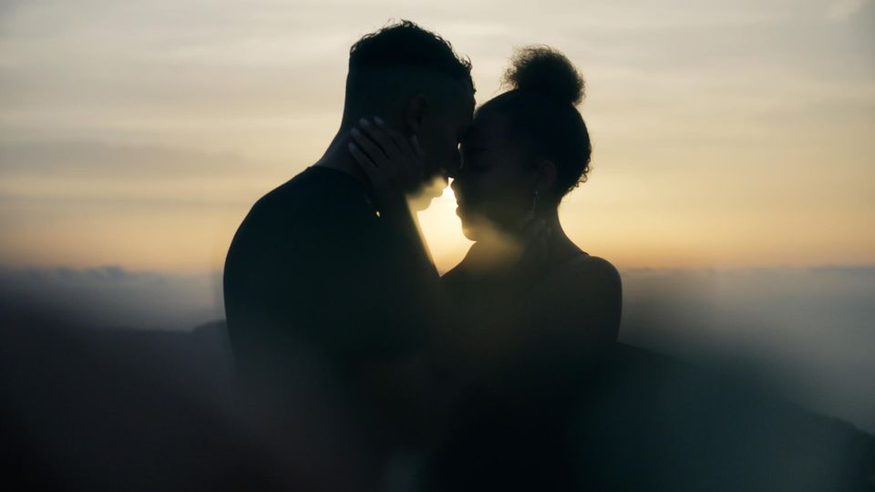 Sex initiieren: Die Silhouette eines Paares, das sich im Sonnenuntergang umarmt